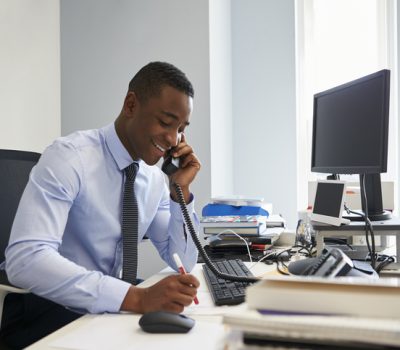 Young black businessman using the phone at his office desk